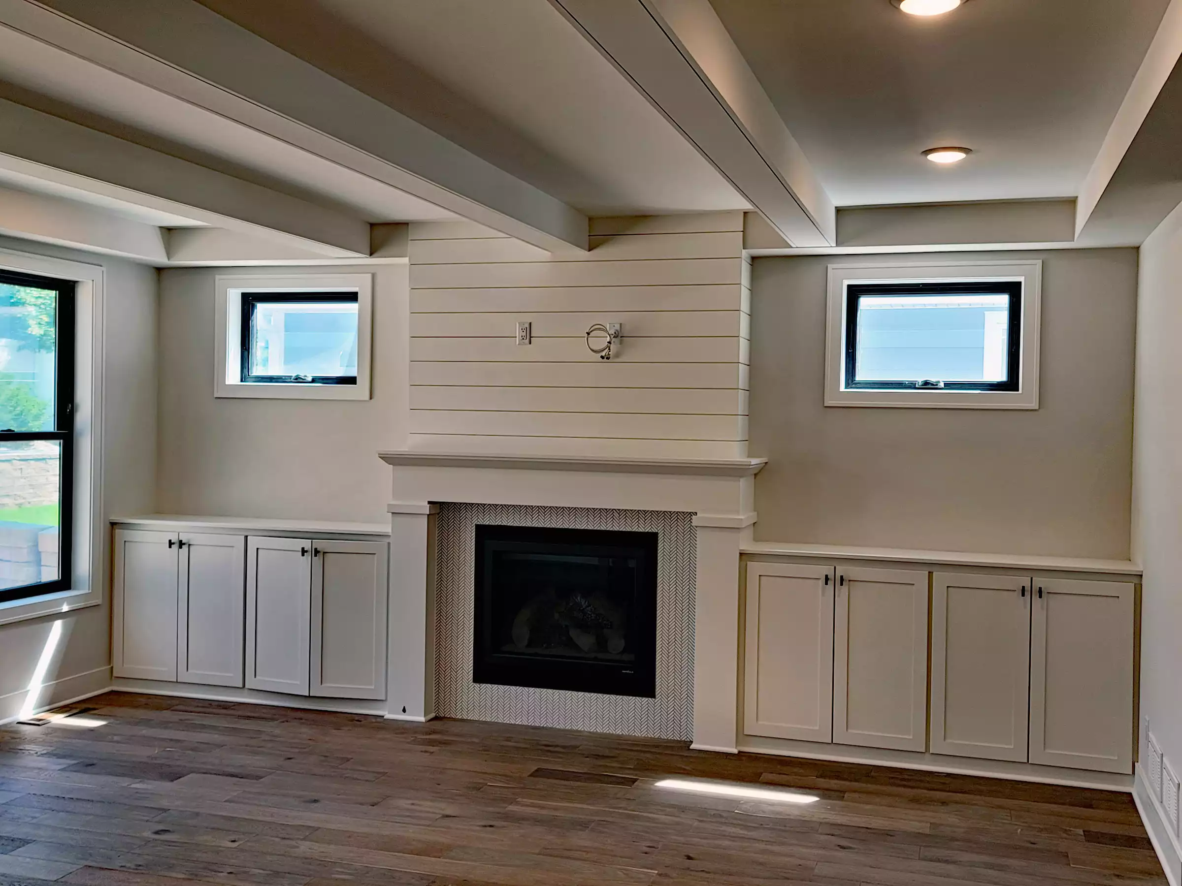 Media wall with fireplace, built-in cabinets and sidelite windows